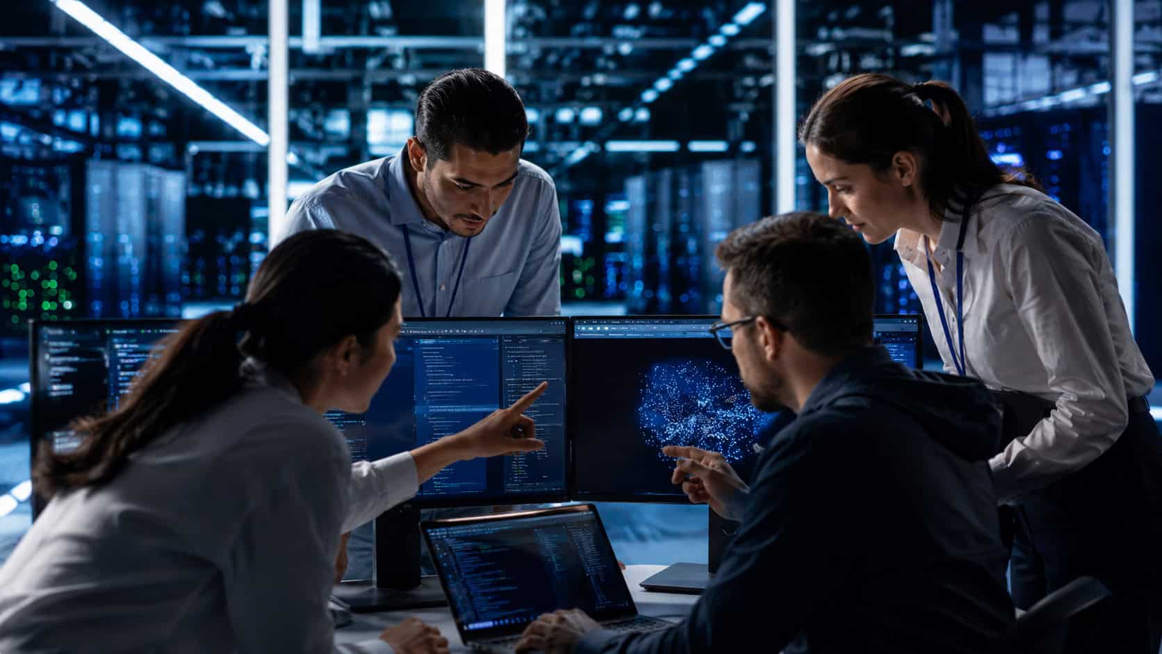 Engineering team collaborating in a data center while reviewing software dashboards and industrial AI analytics on multiple displays.