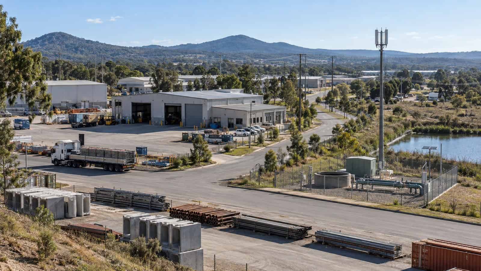 Australian industrial estate combining workshops, a yard, a pump station and restrained cellular infrastructure.