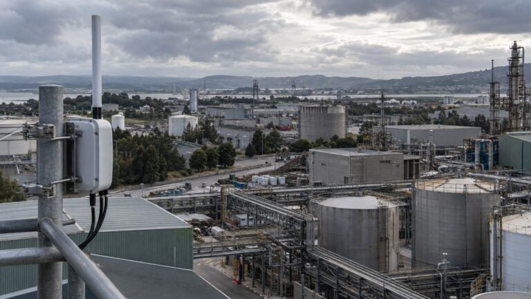 LoRaWAN gateway antenna overlooking a large industrial campus with tanks, pipework and production buildings.
